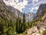 Kings Canyon National Park, California, USA with a view looking into Kings Canyon along the Rae Lakes hiking trail with trees in the foreground and mountains in the distance.