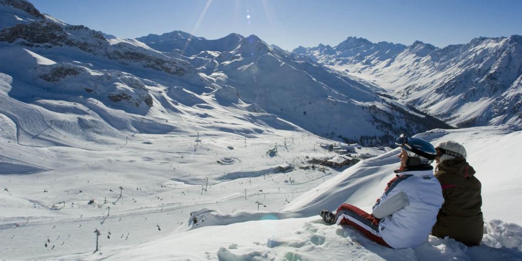 A couple sitting on a ledge looking over the ski slopes at Ischgl below