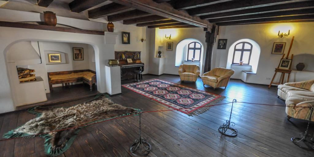 A room in Bran Castle with exposed beams, original furniture and a piano