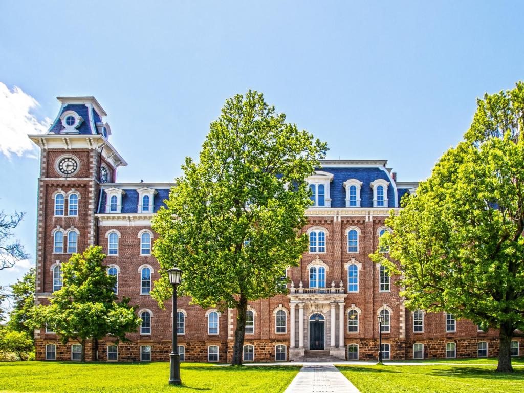 Fayetteville, Arkansas USA with the oldest building on the University of Arkansas campus and one of the most recognizable symbols of the University taken on a sunny day with trees and grass in the foreground. 