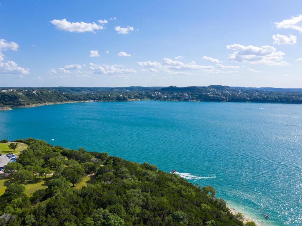 Aerial Shot above deep blue waters of Canyon Lake in the Texas Hill Country on a sunny day. There is a boat in the lake.