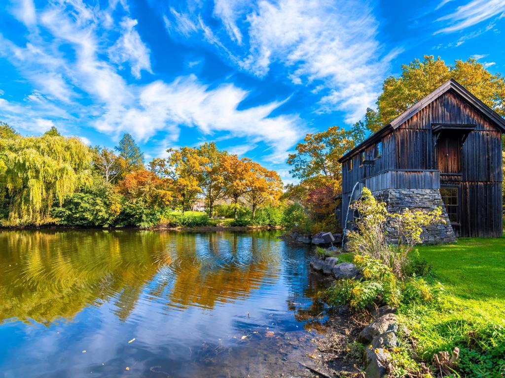 Rockford Town, Illinois, USA with an old watermill in Midway Village of Rockford Town, with water in the foreground and trees in the background taken on a sunny day.