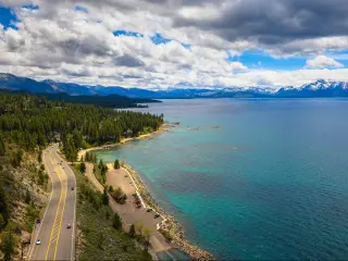 Road running alongside turquoise waters of Lake Tahoe with mountains in the background