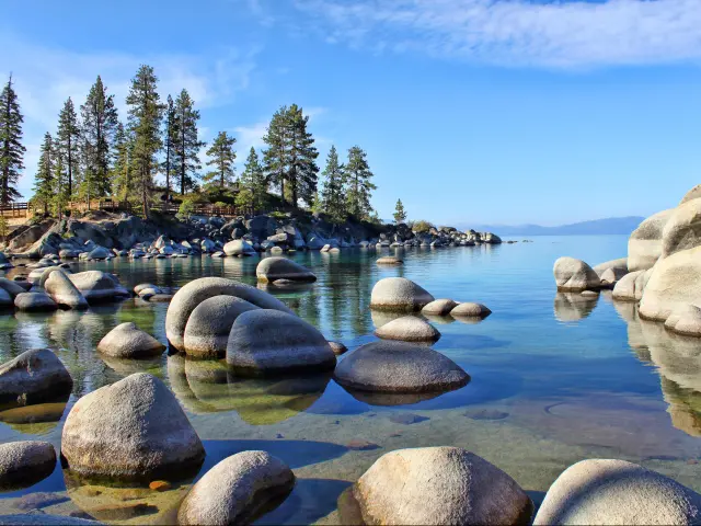 Lake Tahoe, USA taken at early morning with boulders at Sand Harbor in the foreground and trees in the distance.