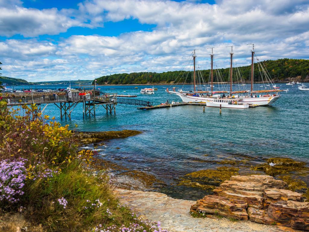 Rocky coast and view of boats in the harbor at Bar Harbor, Maine.