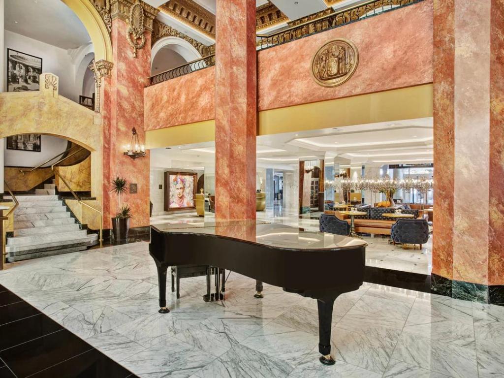 Elegant reception, with grand piano, bar area and marble stairway, at Hotel Paso Del Norte, Autograph Collection