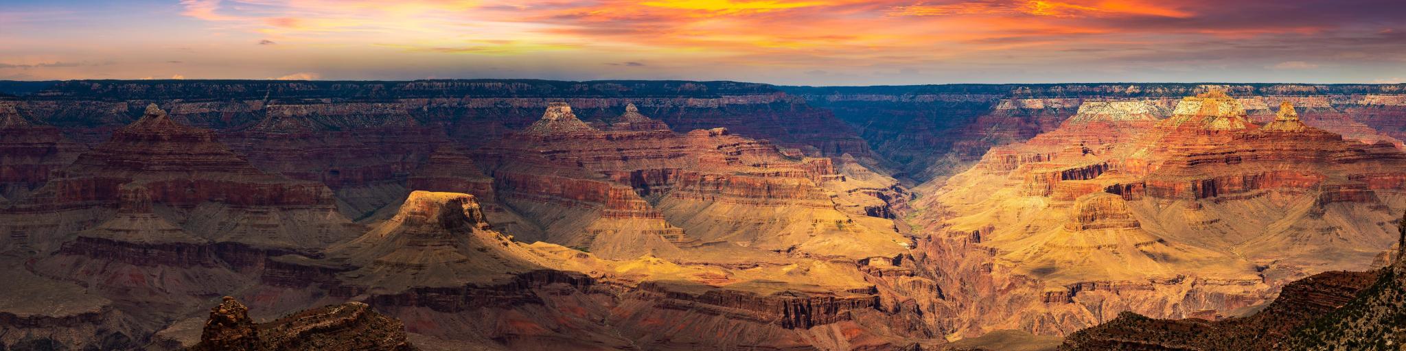 Grand Canyon National Park at sunset, Arizona, USA taken as a panorama with light shining on some of the canyons and a red dramatic sky.