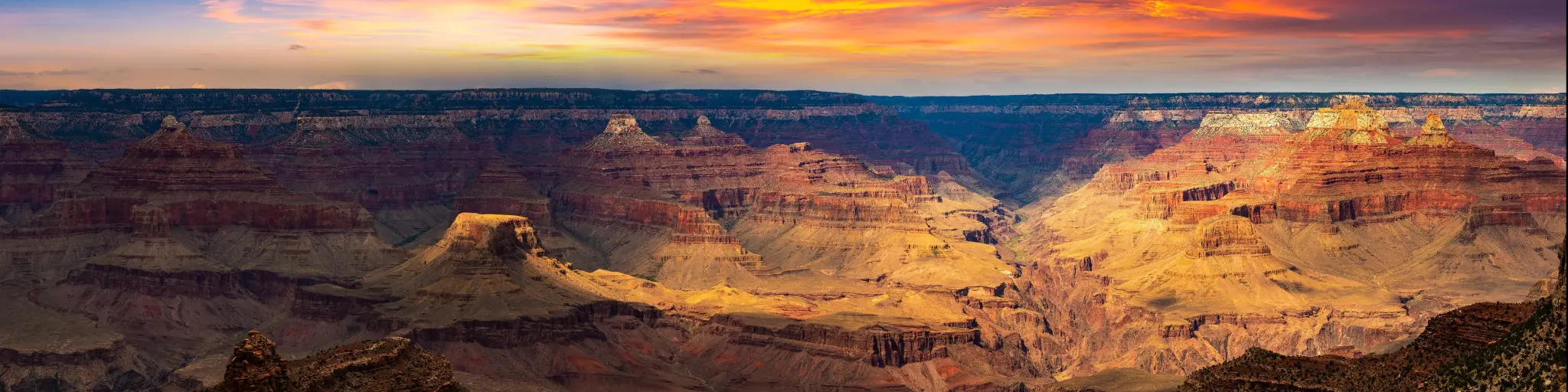 Grand Canyon National Park at sunset, Arizona, USA taken as a panorama with light shining on some of the canyons and a red dramatic sky.