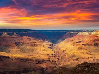 Grand Canyon National Park at sunset, Arizona, USA taken as a panorama with light shining on some of the canyons and a red dramatic sky.