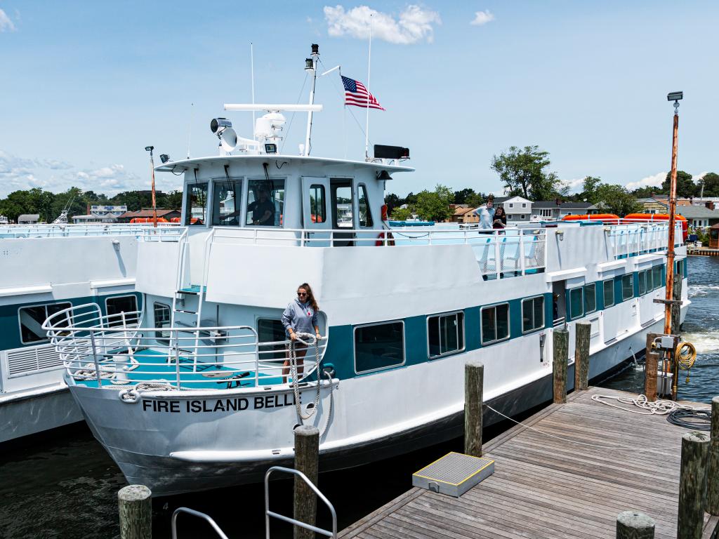 A lady work on board Fire Island Bell is throwing a rope to the ramp as the ship is about to dock the pier.