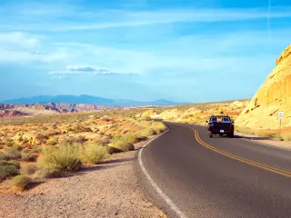 A black car on a winding road in the middle of the desert