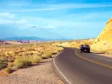 A black car on a winding road in the middle of the desert