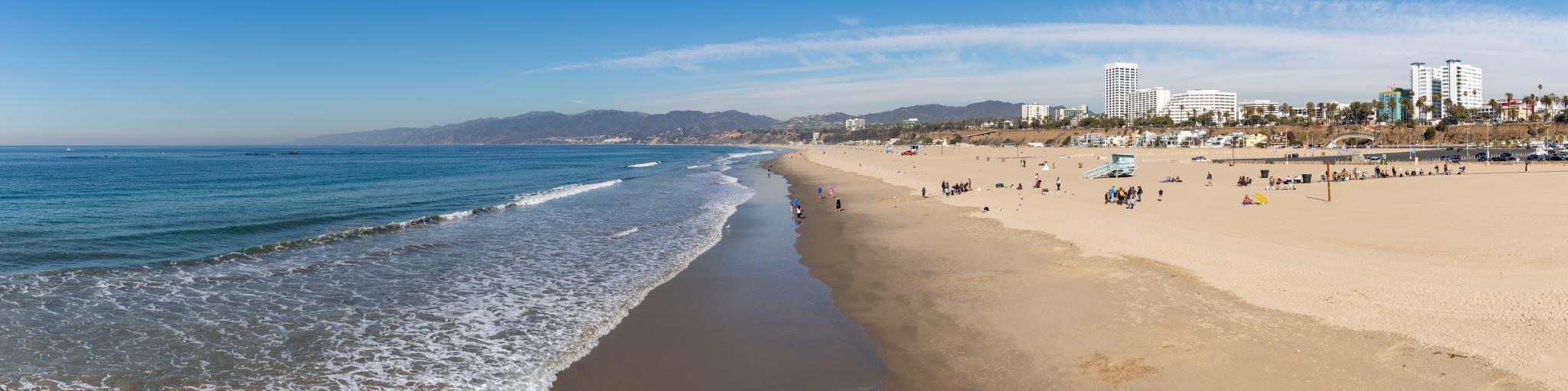 A panorama picture of the Santa Monica State Beach, with waves lapping against sandy shore
