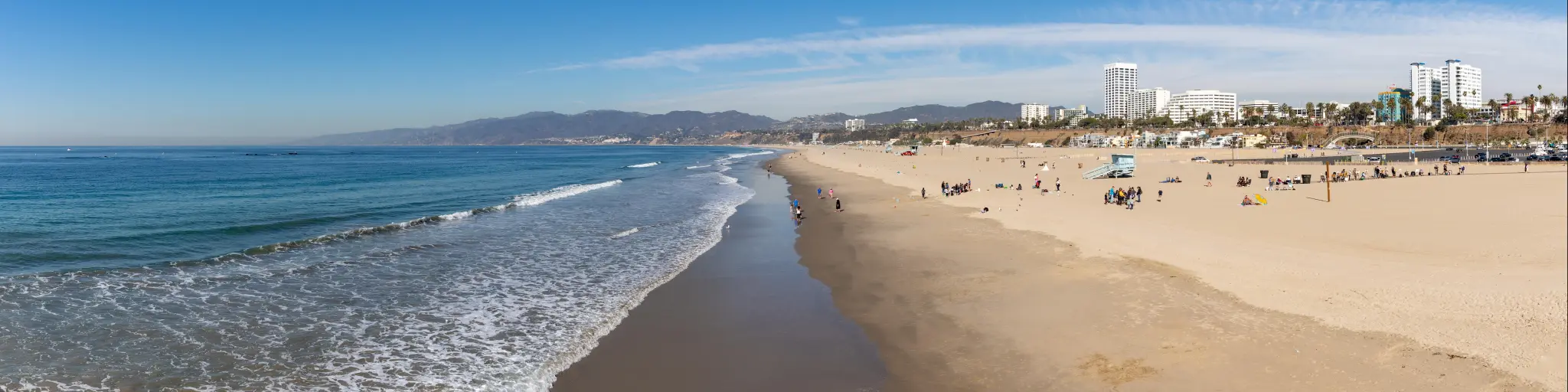 A panorama picture of the Santa Monica State Beach, with waves lapping against sandy shore