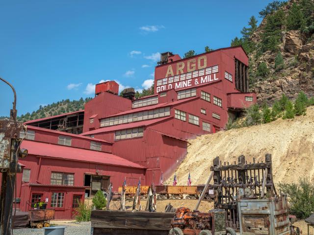 Red historic Argo Gold Mine, Mill and Tunnel in Idaho Springs, Colorado, with disused old machinery in the foreground