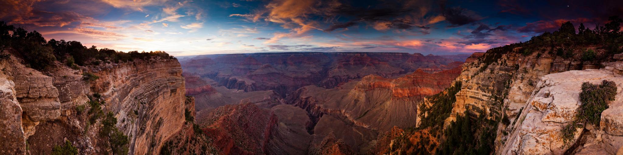 A fantastic view of the sunset reflecting the walls of Grand Canyon with a beautiful hue of pink and purple clouds in the blue sky 
