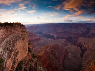 A fantastic view of the sunset reflecting the walls of Grand Canyon with a beautiful hue of pink and purple clouds in the blue sky