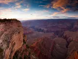 A fantastic view of the sunset reflecting the walls of Grand Canyon with a beautiful hue of pink and purple clouds in the blue sky 