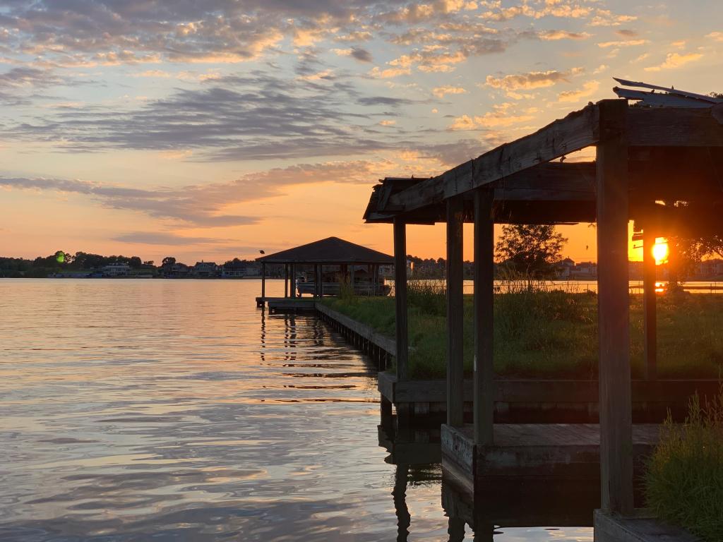 Lake Conroe, Texas, colorful sunset on lake with empty boathouse and green grass