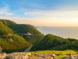Cape Breton, Nova Scotia, Canada with green covered hills in the foreground hills Skyline looking to a valley below and beyond that the sea on a sunny day.