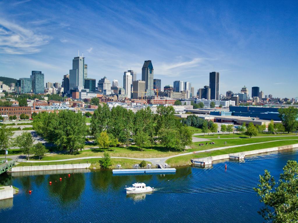 Montreal, Canada with the city skyline in the background and a yacht in the foreground in the Lachine Canal taken on a sunny day. 