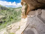 View inside Gila Cliff Dwellings National Monument with mountains and forests dotted in background