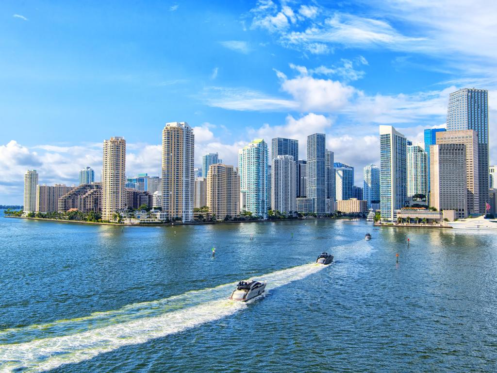 Aerial view of Miami skyscrapers with blue cloudy sky, white boat sailing next to Miami downtown