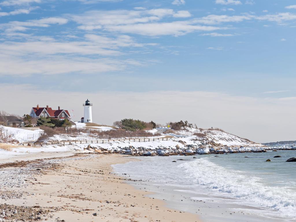 Snow-dusted beach and the lighthouse in the background during winter