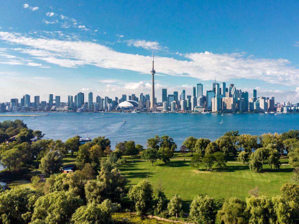 Lake Ontario, Toronto, Ontario, Canada with the city skyline in the background and Lake Ontario and a green park in the foreground on a clear sunny day. 