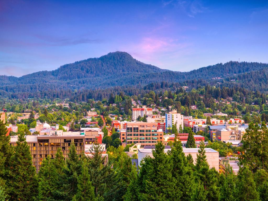 View of the city of Eugene at dusk, with mountains in the background.