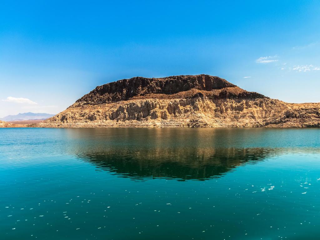 Lake Mead, National Recreation Area, Nevada, USA with a big sedimentary rock formation surrounded by clear water on a sunny day.