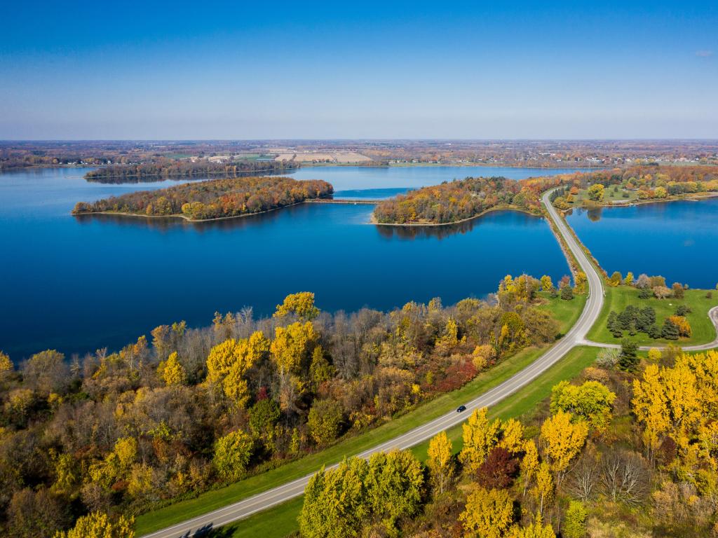 Road crossing a channel between many small islands with vibrant green trees and bright blue water and sky