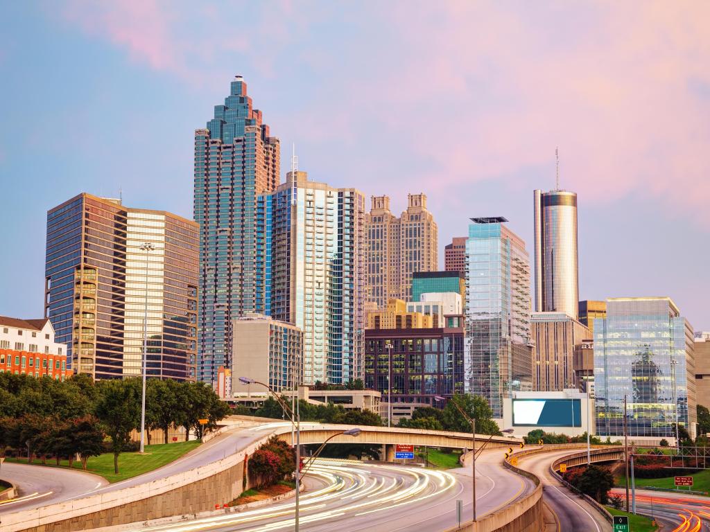 Highway passing through Atlanta downtown with highrise buildings lit up in light pink light