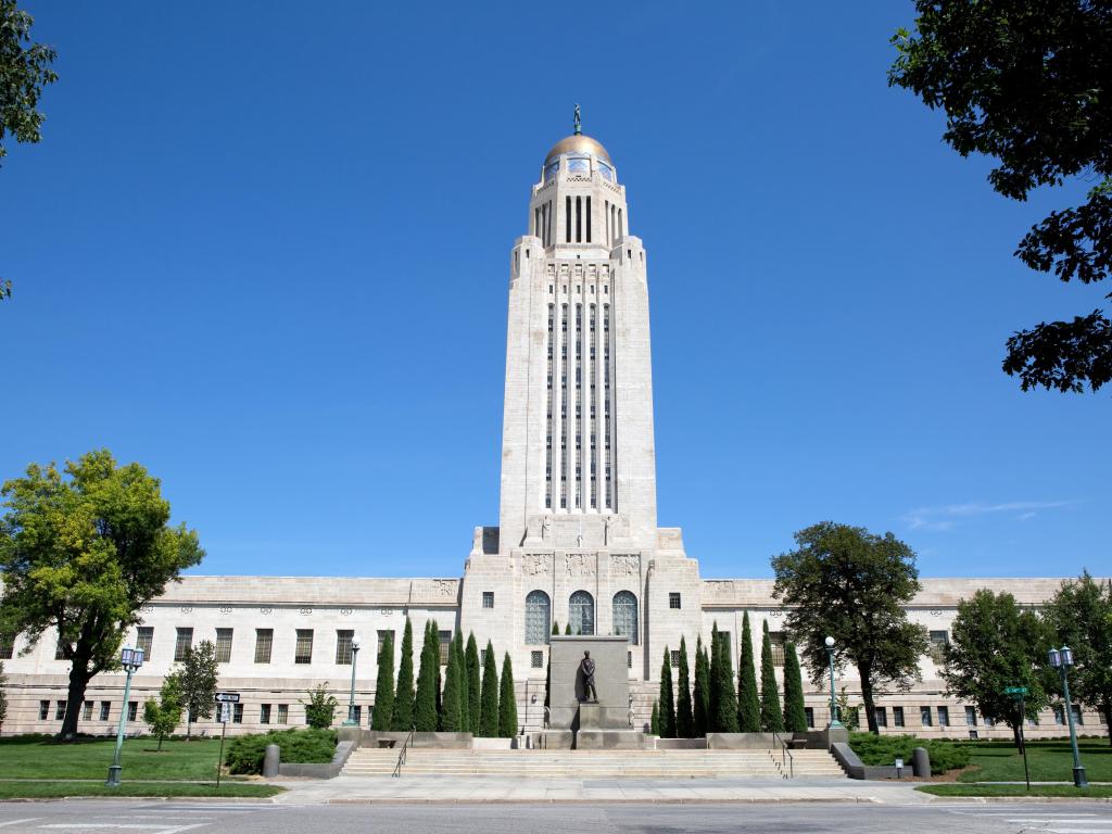 Lincoln, Nebraska, USA taken at the Nebraska State Capitol building a clear sunny day with trees lining the road.