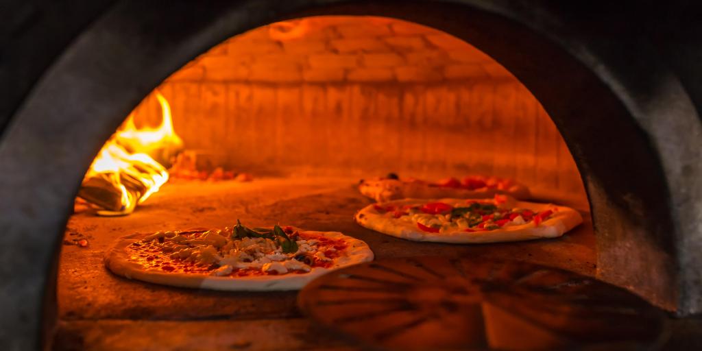 Pizza being cooked in a wood-fired oven in Naples 