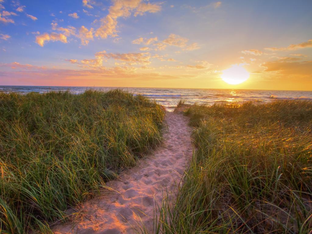 Path To A Sunset Beach. Winding trail through dune grass leads to a sunset beach on the coast of the inland sea of Lake Michigan. Hoffmaster State Park. Muskegon, Michigan.