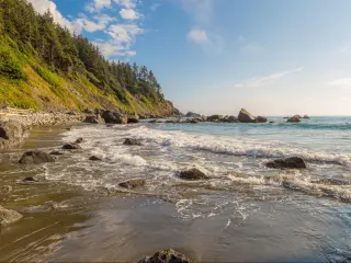 Redwood National Park Redwood National Park, California, USA with large boulders among the waves in the sea and trees in the distance on a sunny day.