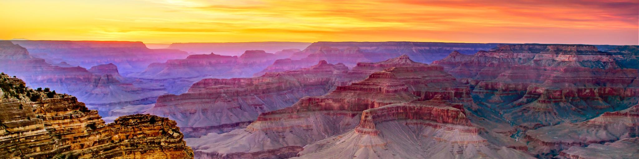 A view of the famous Grand Canyon South Rim at sunset, with a multicolored sky above the vast canyon below