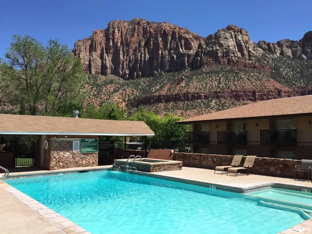 View of swimming pool surrounded by accommodation, and views of the Zion Mountains in the background.