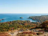 Camden Hills State Park, Maine in autumn with a view of the harbour from the summit of Mount Battie in the foreground against a blue sky and the sea in the distance. 