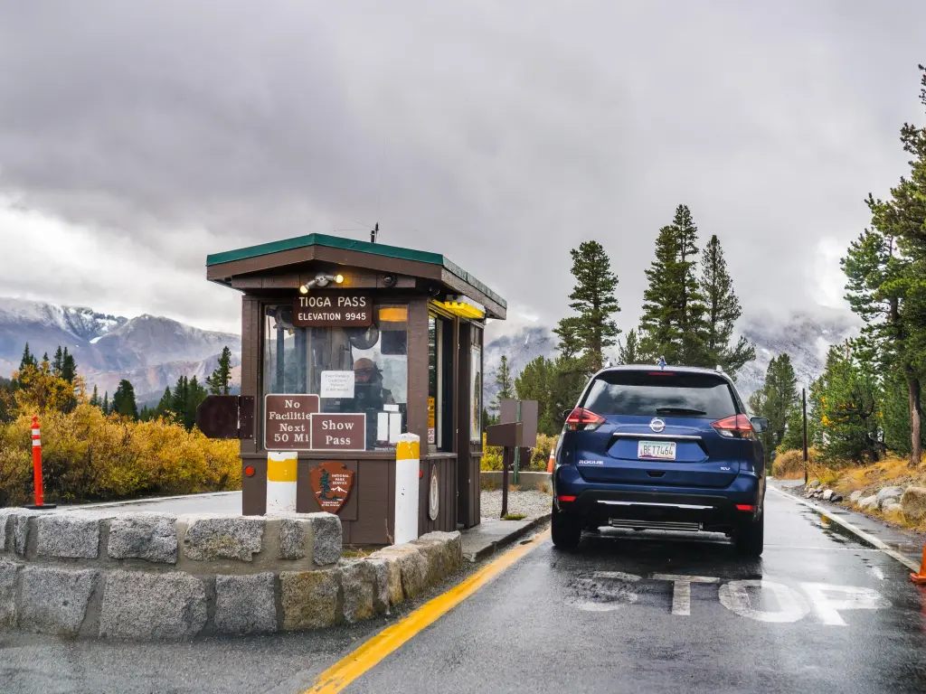 Tioga Pass Entrance on a rainy day, with a blue car waiting to pay for the ticket