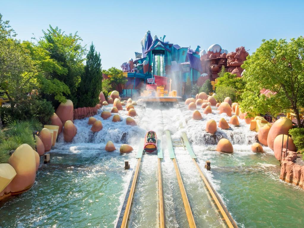 A ride lands with a splash at Universal Studios, with colorful ride building in the background