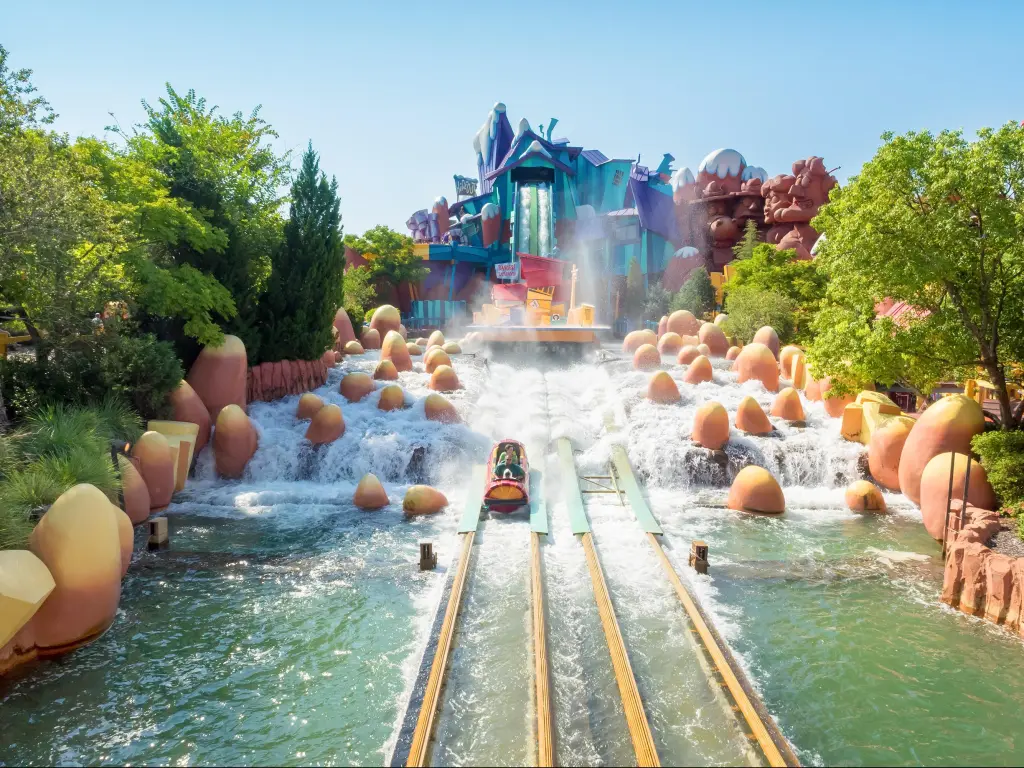 A ride lands with a splash at Universal Studios, with colorful ride building in the background