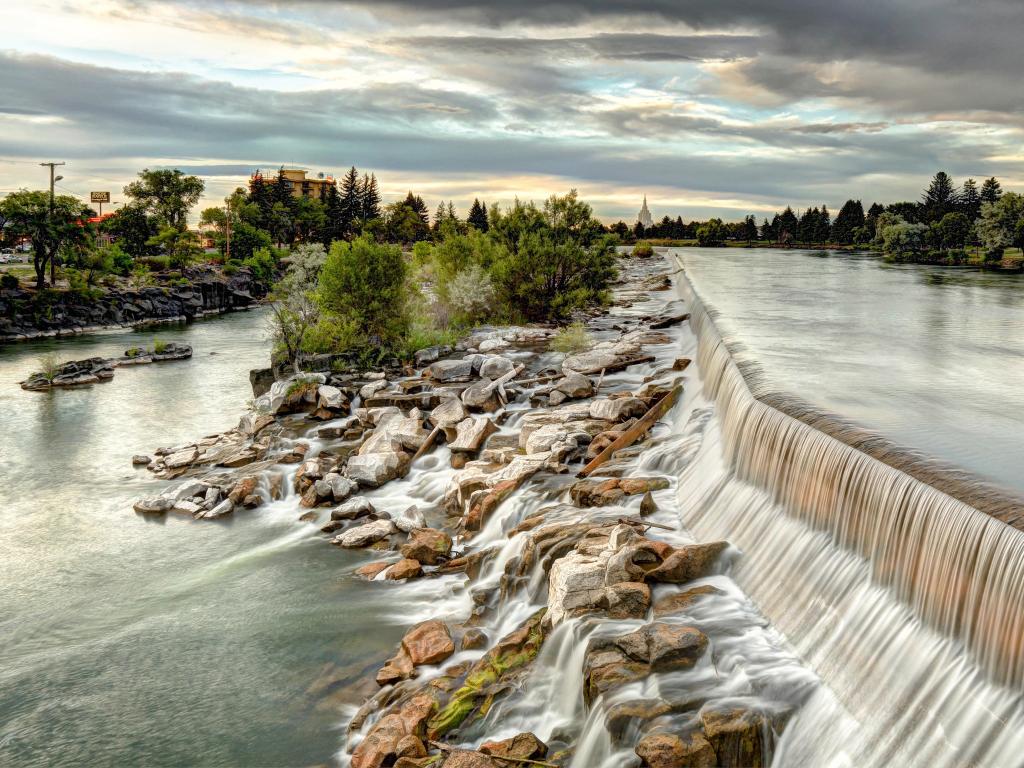 Idaho Falls, Idaho, USA with the waterfall in the foreground and trees in the distance. 