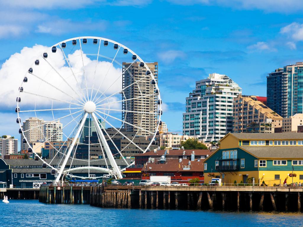 Seattle Great Wheel, waterfront and skyline on a bright sunny day with blue sky and clouds. The close-up view is from the water. 