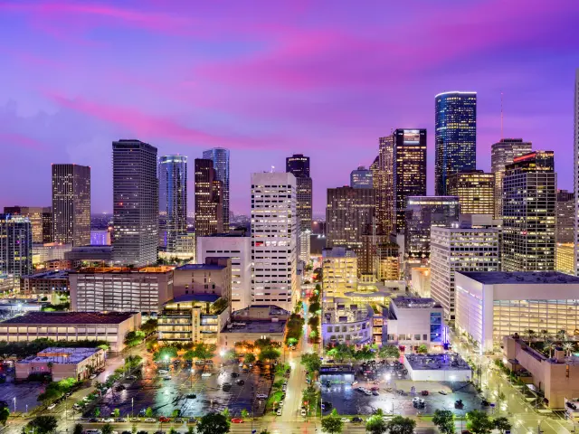 Skyline of the city during a pink and purple sunset with the buildings lit up 