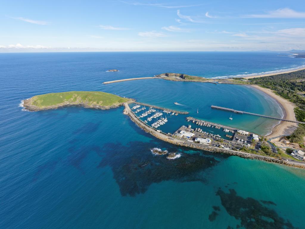 Coffs Harbour, Australia with the Marina leading to Corambirra Point, surrounded by a turquoise blue sea and bright blue sky.