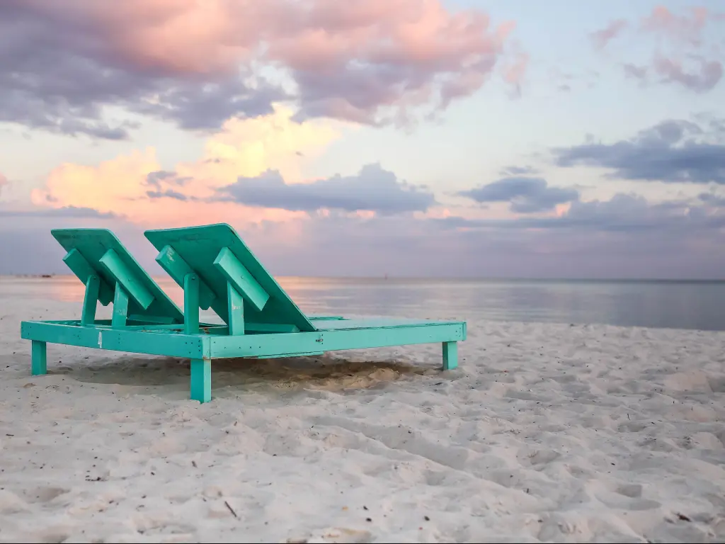 A white sand beach with turquoise wooden sun loungers at Biloxi, Mississippi