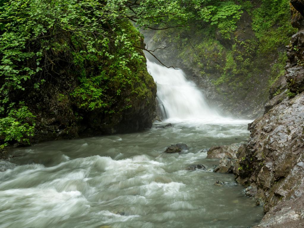 Thunderbird Falls in Alaska with rocks and trees either side of the waterfall. 