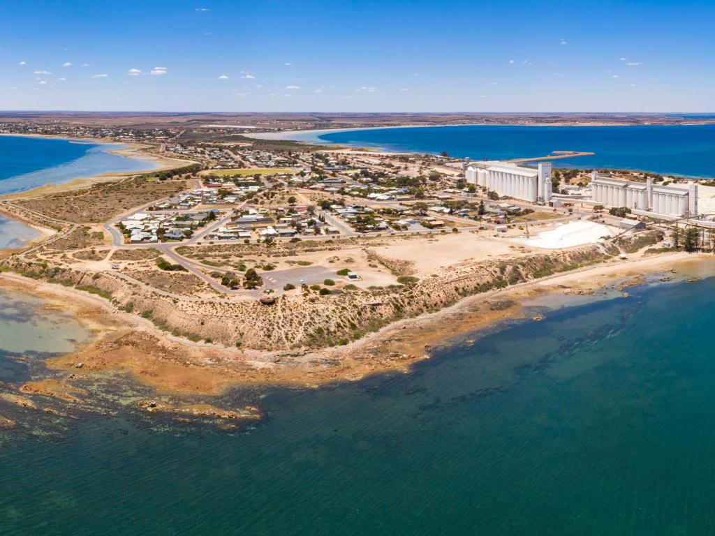 Ceduna, South Australia taken as an aerial shot showing the harbour and a fishing boat in the sea surrounded by blue sky.